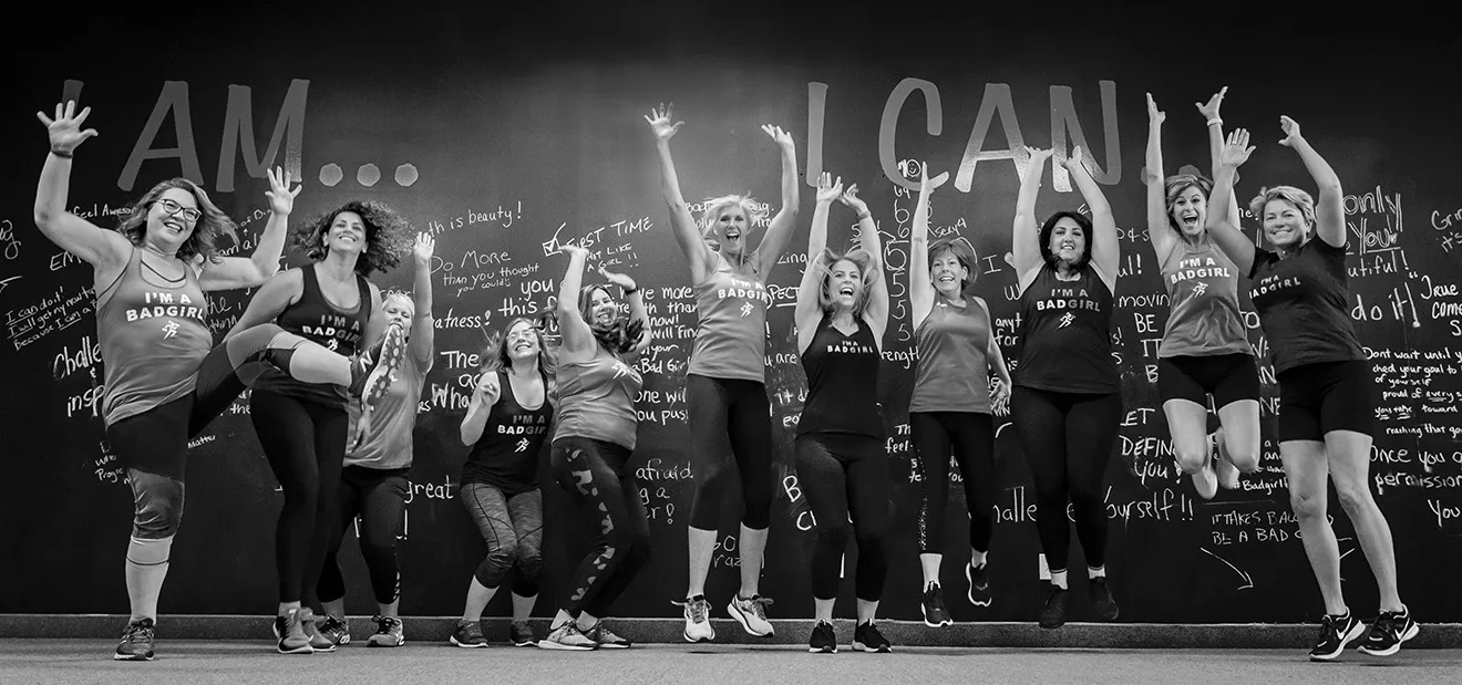 Bad Girl Fitness members jumping and celebrating together at the studio wall
